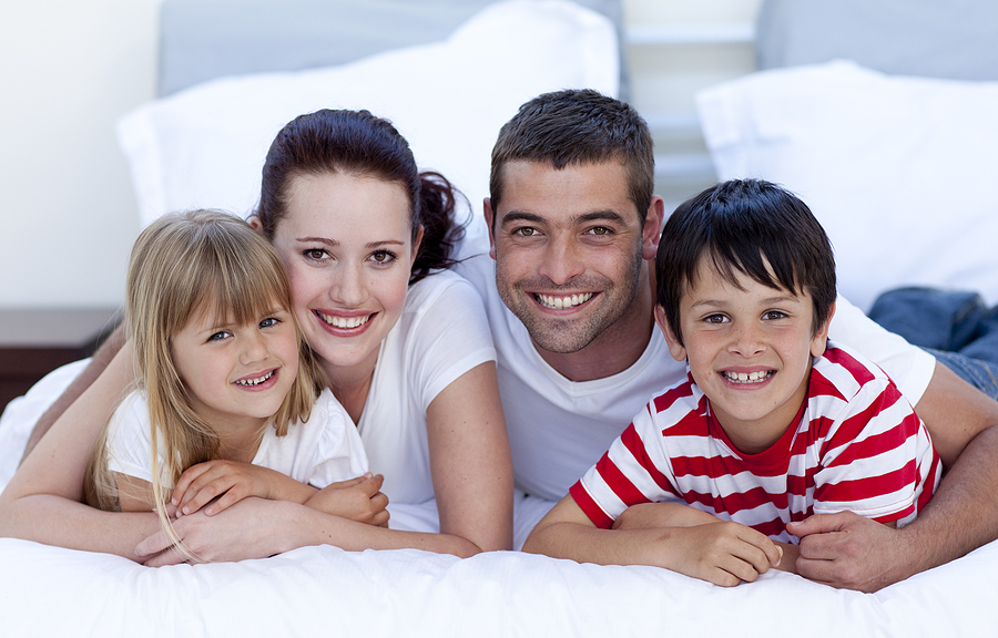 Smiling Family Lying In Bed Together