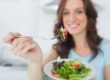 Woman eating healthy salad in her kitchen.